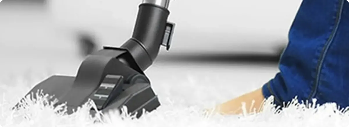 Close-up of a professional vacuuming a white carpet in Brighton.